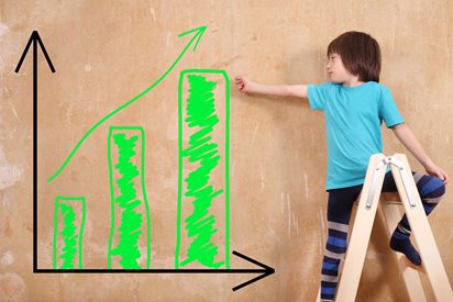 Child on ladder pointing to bar graph on chalk board